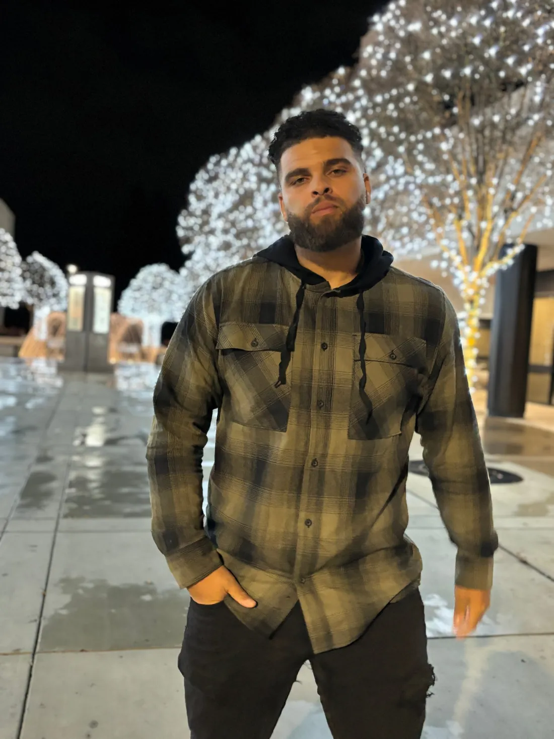 Coach Crim in a flannel, standing in front of trees wrapped in lights